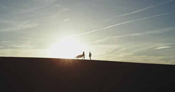 At sunset faraway couple very rom running through the large beach they have a good time