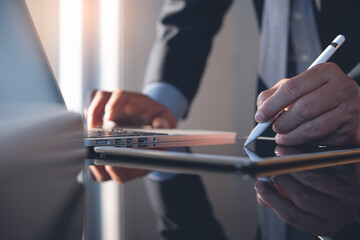 Businessman working on digital tablet and laptop computer for business analysis in office
