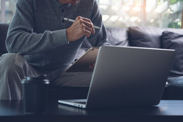 Casual man freelancer working on digital tablet and laptop computer at home office