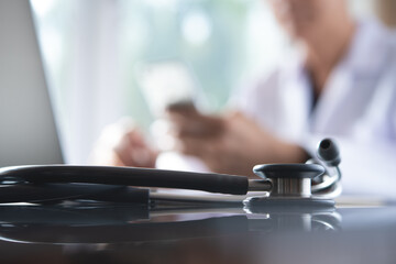 Doctor working on laptop using mobile phone for telemedicine or teleconference