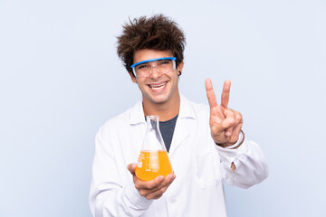 Young scientific man over isolated blue background smiling and showing victory sign