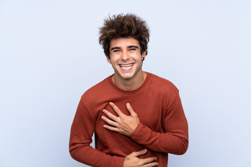 Young caucasian man over isolated blue background smiling a lot