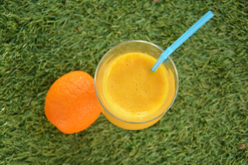 Glass of  fressh orange juice on the grass 