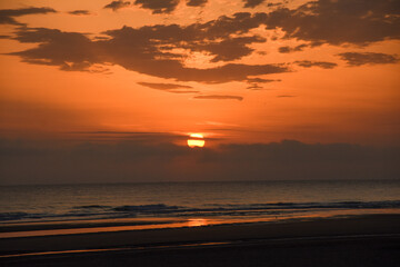 Amanecer en la playa con el sol entre las nubes