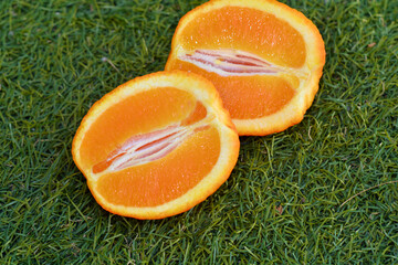Orange cutted on two halfs on the green grass 