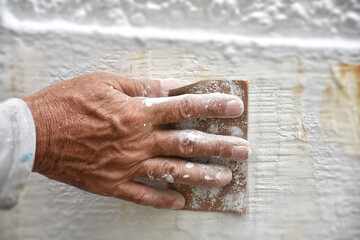 Sanding the wall before painting.