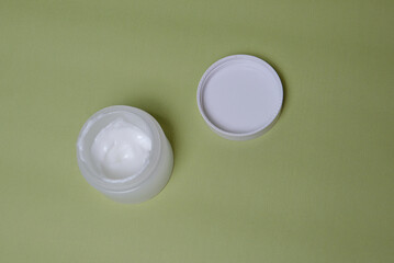 white jar of cream on a green background