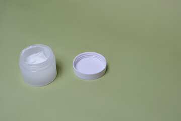 white jar of cream on a green background