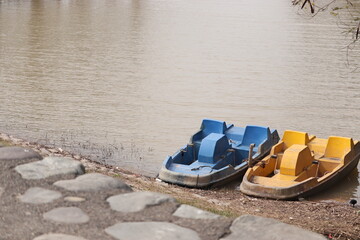 Two abandoned pedal boats at the lake shore