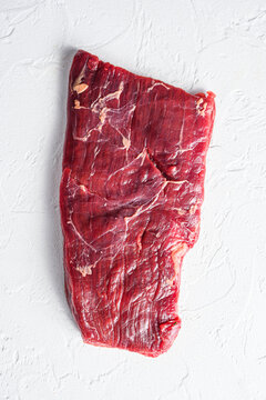 Raw skirt or flank steak,on a white stone background top view vertical