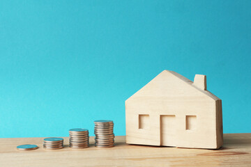 Wooden house and stacks of coins. Real estate investment for buying own home.  The accumulation of money for housing. 