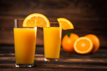 Fresh orange juice in the glass cup with oranges on old wooden table.