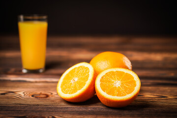 Fresh orange juice in the glass cup with oranges on old wooden table.