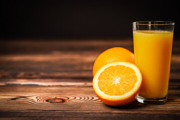 Fresh orange juice in the glass cup with oranges on old wooden table.