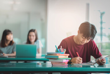 A young man reading and writtening book with many books, happy education university concept.