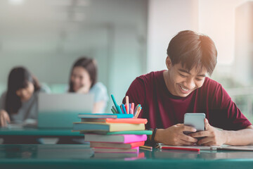 A young man reading and writtening book with many books, happy education university concept.
