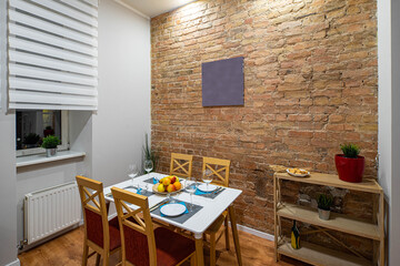 Modern contemporary interior of kitchen in loft apartment. Brick wall. Table and chairs.