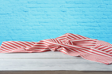 Empty wooden table with striped tablecloth over blue brick wall. 4th of july USA independence day...