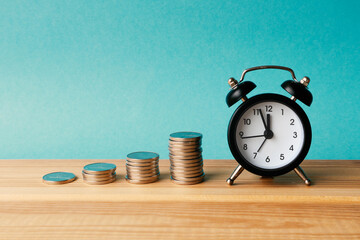 Piles of coins in ascending order and alarm clock on a dark background. Profit growth over time....