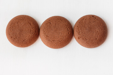 Three round brown chocolate cookies on white background top view