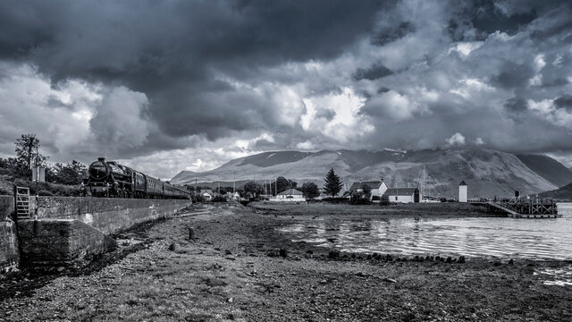 Steam Train runs alongside Loch Eil with the Corpach Lighthouse on the right and Ben Nevis as a backdrop