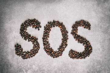 SOS text made from coffee beans on a light gray background. Request for help.