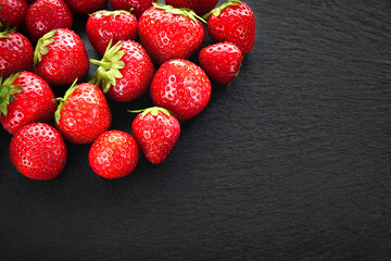 Bunch of strawberries background. Strawberries on a dark slate stone. Background image with copy space. Healthy berries.