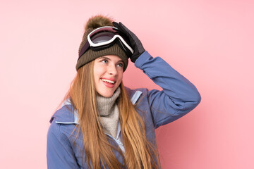 Skier teenager girl with snowboarding glasses over isolated pink background laughing