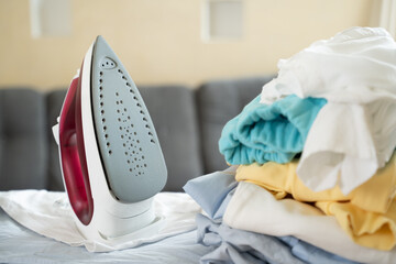 Electric iron and pile of clothes on ironing board