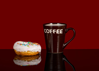 Tasty donut and white cup of coffee with coffee on a red background with reflection