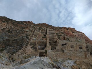 Destroyed sulfur factory in the mountains. Broken brick buildings with stairs. Greece. Milos island. Summer