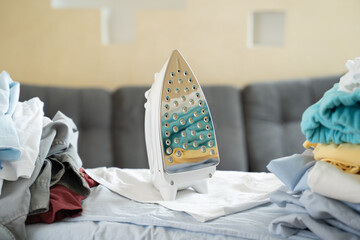 Electric iron and pile of clothes on ironing board