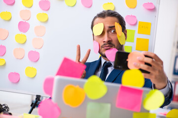 Young male employee in conflicting priorities concept