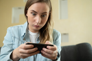 Cheerful happy, smiling young woman playing smartphone game, holding mobile phone horizontally as passing race level, cars game.