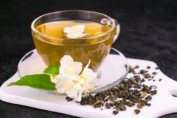 
A cup of jasmine tea and jasmine flowers on a black background.
Close-up.