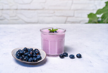 Tasty fresh blueberry yoghurt shake dessert in glass standing on white table background.