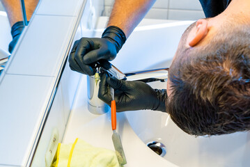 professional cleaner descaling a bathroom sink tap with a scraper and scale pick before finishing and polishing