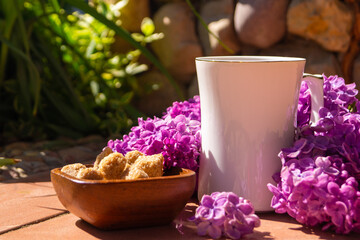 white porcelain cup with tea and among flowering branches of lilac