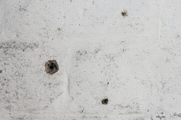 The old wall is white.  traces of shots, holes