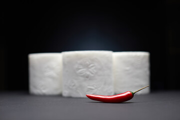 Red chili pepper in focus sharp near the toilet papers in blur  like pain symbol from hemorrhoid or menstruation symptom isolated on blue background