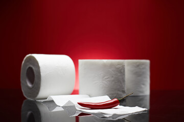 Red chili pepper near the toilet papers like pain symbol from hemorrhoid or menstruation symptom isolated on blue background