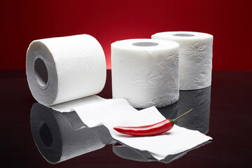 Red chili pepper near the toilet papers like pain symbol from hemorrhoid or menstruation symptom isolated on blue background