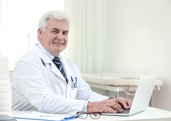 Portrait of senior doctor in white coat at workplace