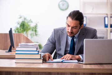 Young male businessman reading books at workplace