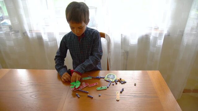 Education, children, technology, science and futuristic concept. E-learning. The boy is played by an electronic constructor. Intellectual toys. Early development concept.