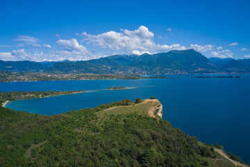Fototapeta na wymiar Lake Garda, Italy. Aerial view of punta sasso, rocca di manerba in the background mountains, san biagio island, garda island at high altitude