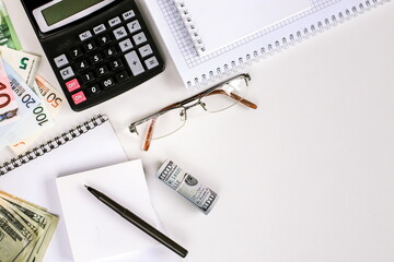 Office workplace, money, calculator and stationery on the table top view. Dollars, euros