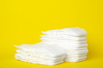 Stacks of baby diapers on yellow background