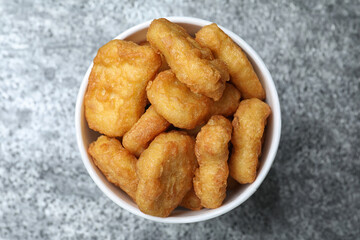 Bucket with tasty chicken nuggets on grey table, top view