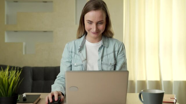Beautiful young woman working on laptop computer while sitting at the living room
